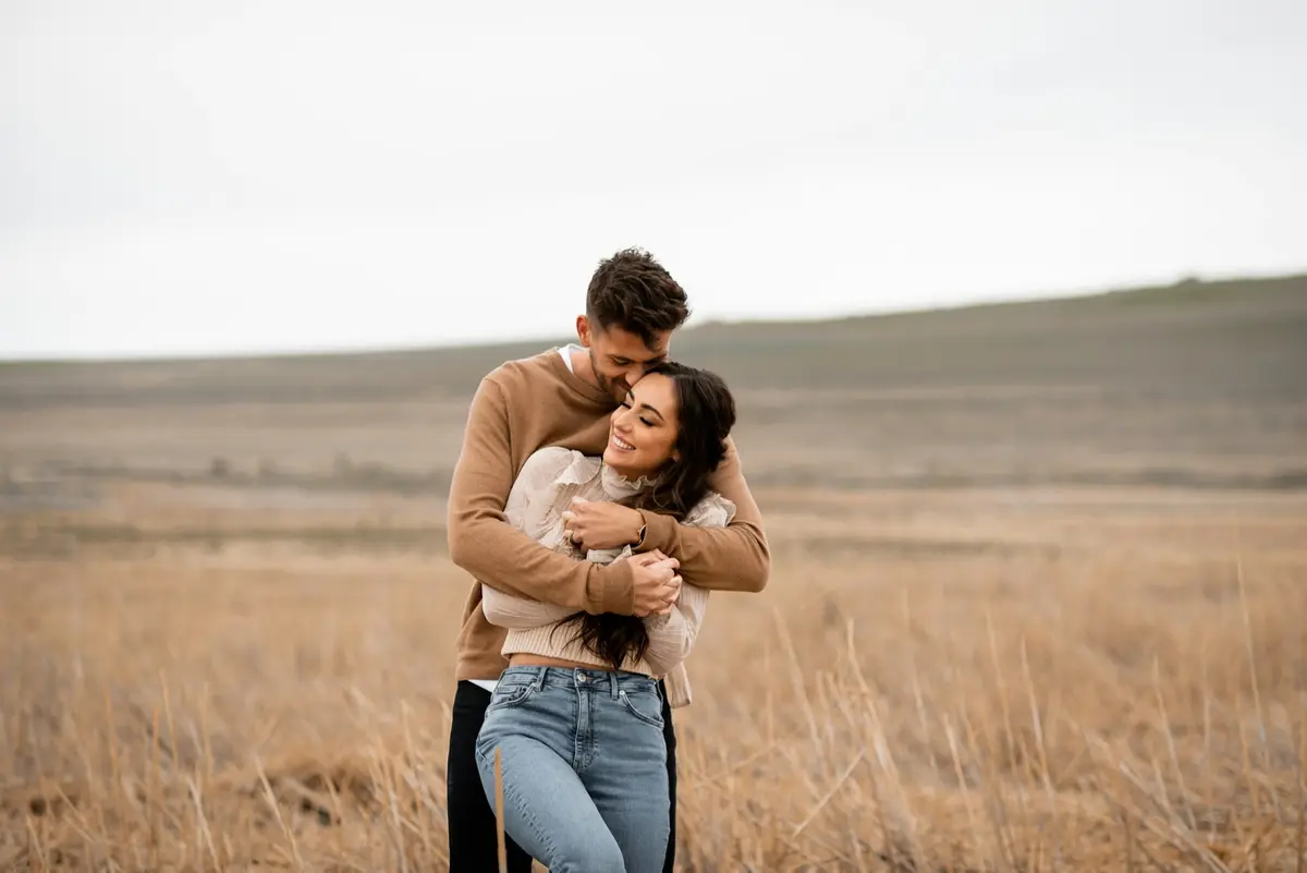 A couple embracing in a golden field at sunset