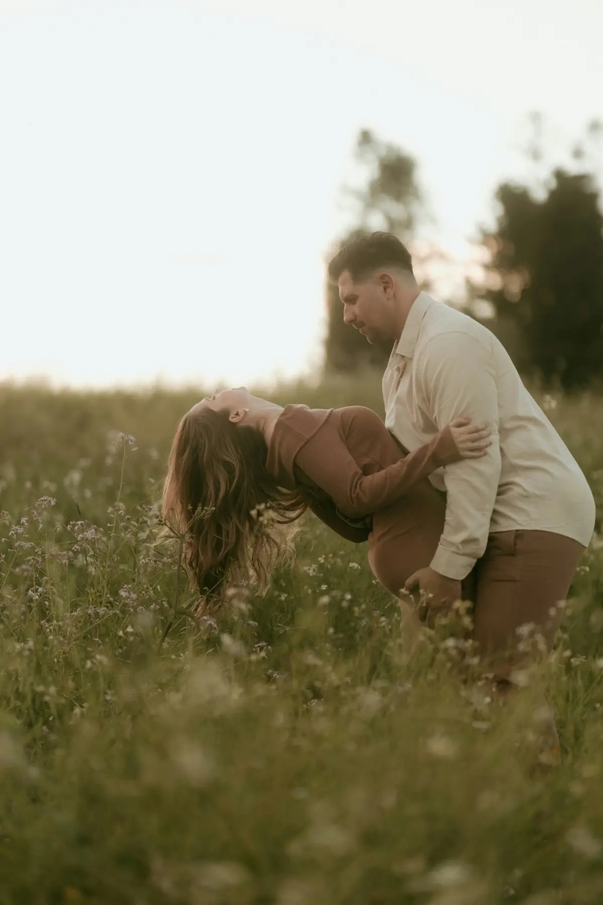 A couple standing together in a tall meadow