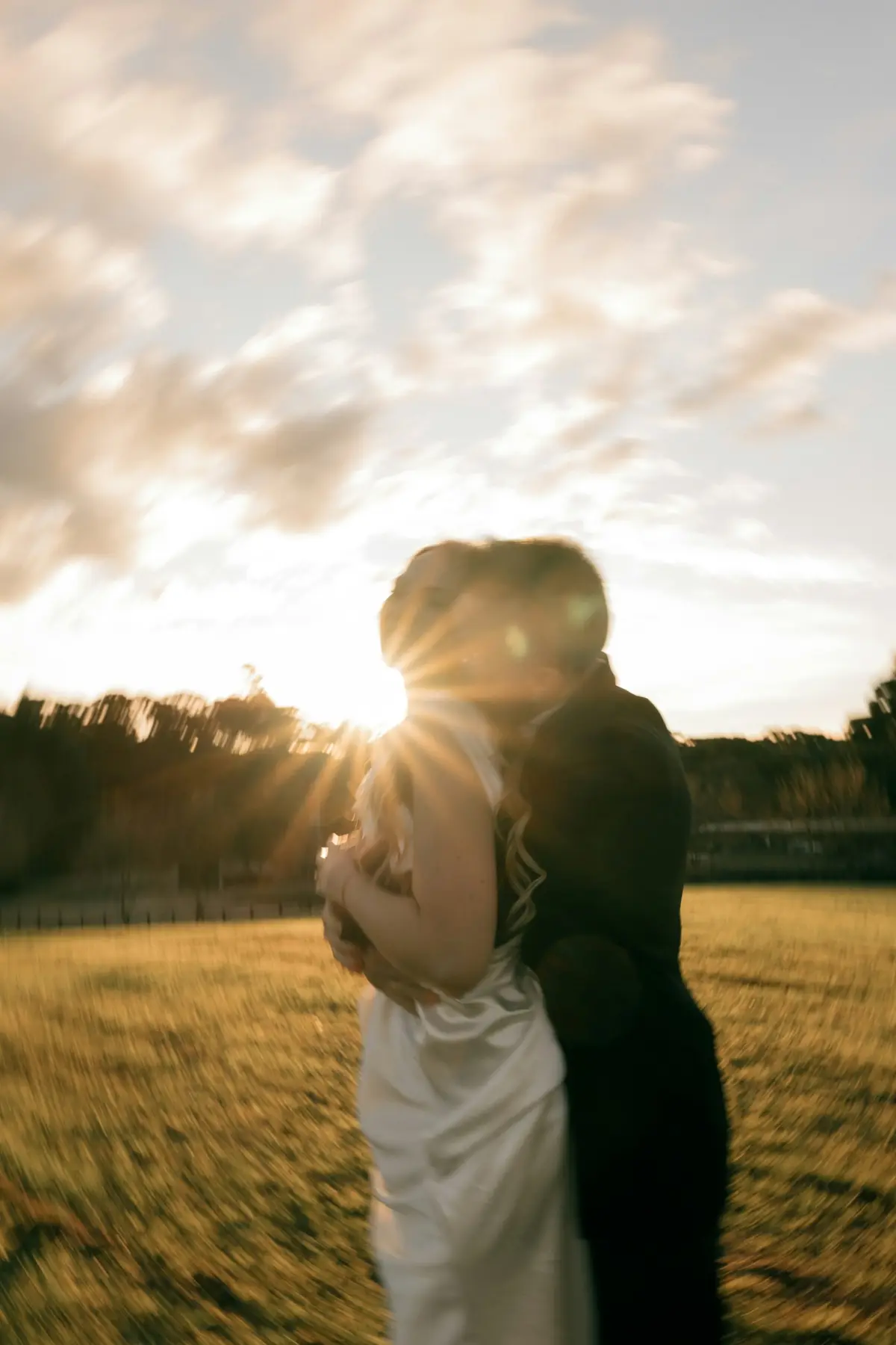 A couple kissing with the sun bursting behind them